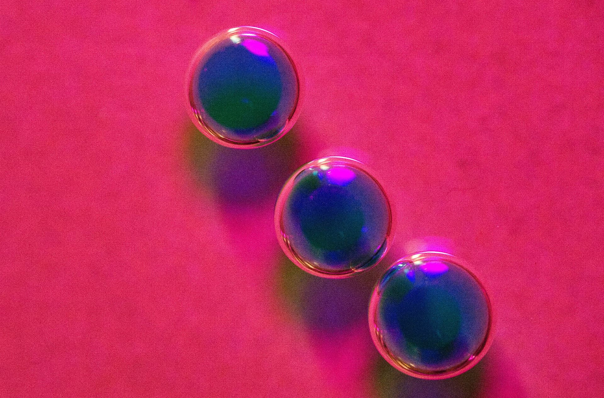 Glass spheres catching light on a vivid pink surface